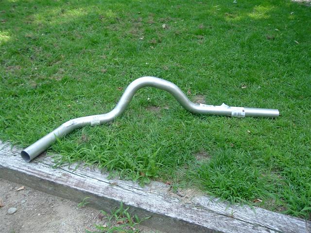 New aluminized exhaust tailpipe with axle hump bend lying on grass