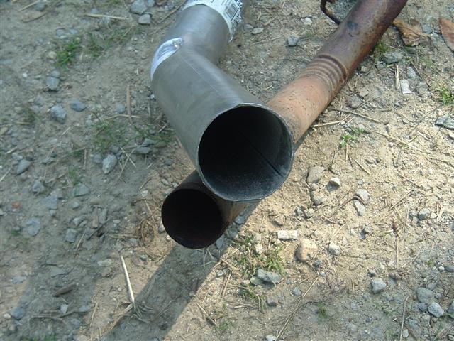 Rusty branched exhaust pipe assembly lying on the ground
