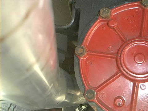 1978 Ford Bronco - Close-up of a red automotive part next to a metallic pipe.