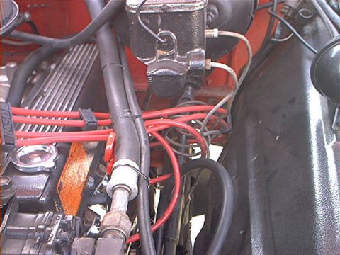1978 Ford Bronco - Engine-bay close-up of a red-painted V8 fitted with a finned MSD valve cover and bright red spark-plug wires, with a black brake master cyl…