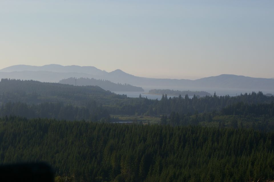 Hazy mountain range over dense forest and a body of water