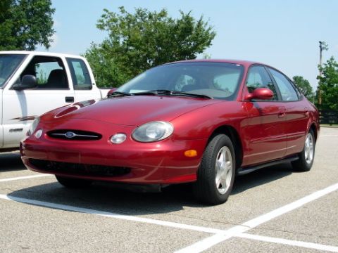 1991 Ford Probe - A red sedan is parked in a lot next to a white pickup truck.