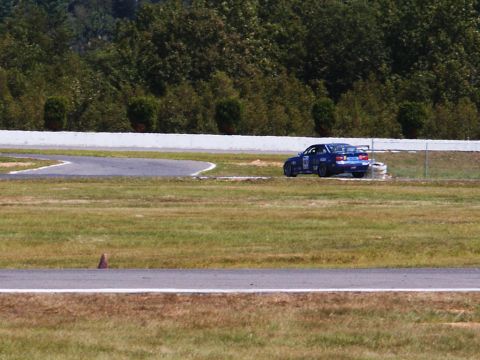 2001 Mercury Grand Marquis - A blue sedan with racing modifications navigates a turn on a race track.