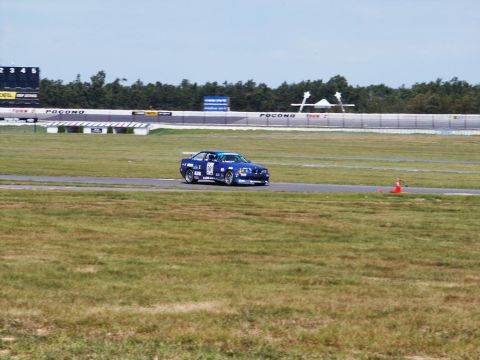 2001 Mercury Grand Marquis - A blue race car with the number 81 is seen on a race track with grandstands in the background.