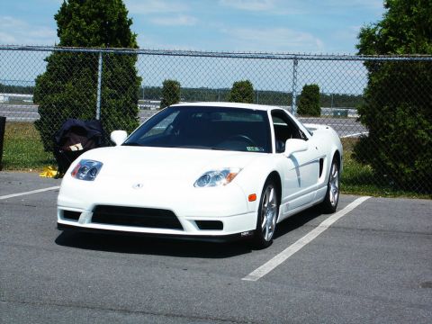 2001 Mercury Grand Marquis - A white Acura NSX is parked in a lot under a blue sky with some trees and a fence in the background.