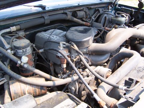 1993 Ford Bronco - Close-up view of a vehicle's engine compartment, showing various mechanical parts and hoses.