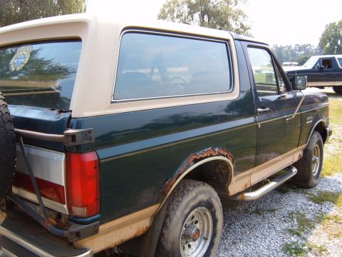 1993 Ford Bronco - Side view of a classic Ford Bronco, showing its two-tone paint and signs of wear.