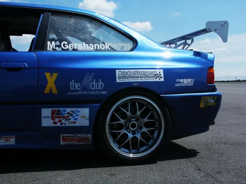2001 Mercury Grand Marquis - A blue race car is seen from the rear quarter panel, a large spoiler and various racing decals on its body.