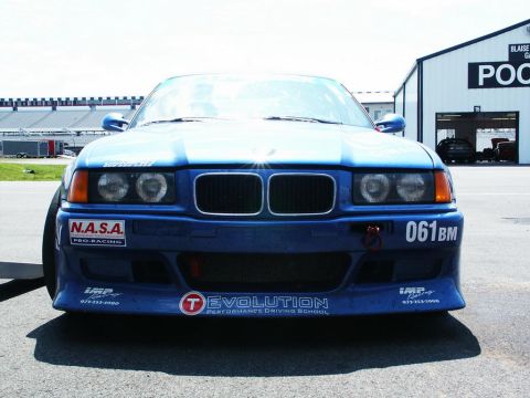 2001 Mercury Grand Marquis - Front view of a blue BMW E36 M3 race car with "Evolution Performance Driving School" and "N.A.S.A. PRO RACING" decals.