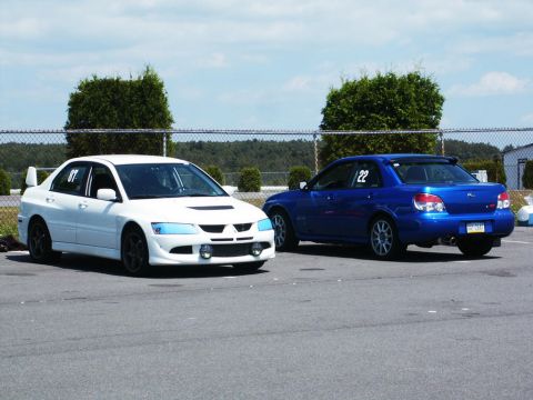 2001 Mercury Grand Marquis - Two sedans, one white and one blue, are parked on a paved surface under a partly cloudy sky.