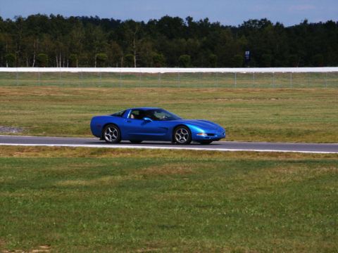 2001 Mercury Grand Marquis - A blue Chevrolet Corvette C5 is seen driving on a racetrack during the day.