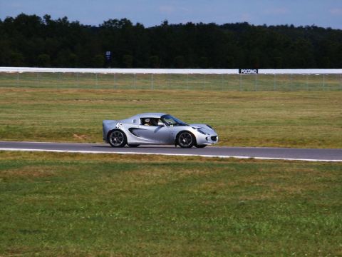 2001 Mercury Grand Marquis - A silver sports car is seen on a race track with trees and a fence in the background.