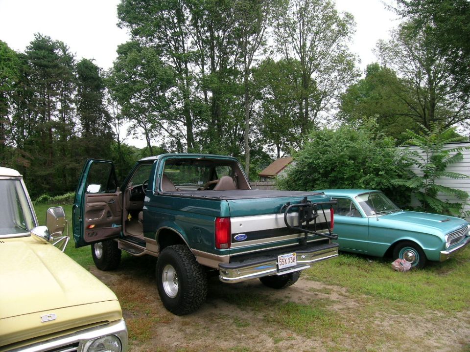 Green Ford Bronco with doors open parked next to a teal Ford Falcon