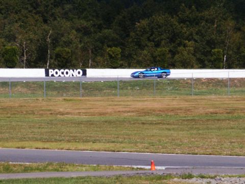 2001 Mercury Grand Marquis - A blue sports car drives on a race track with a 'Pocono' sign in the background.