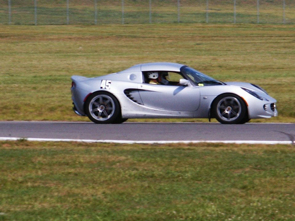 Silver sports car with number 45 on the side, driver wearing a helmet, on a race track