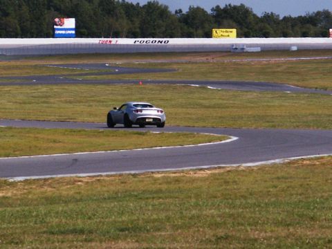 2001 Mercury Grand Marquis - A silver sports car navigates a turn on a race track, with track signage visible.
