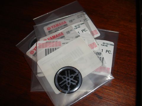 1993 Ford Taurus - Several Yamaha emblems are packaged individually on a wooden table.