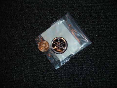 1993 Ford Taurus - A Yamaha emblem is shown next to a penny, both resting on a dark, textured background.