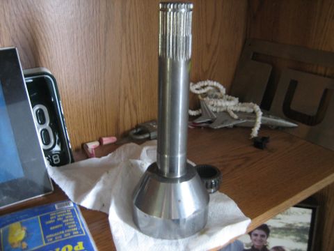 1986 Ford F-150 - A metal shaft with splines and a conical base is shown on a shelf.
