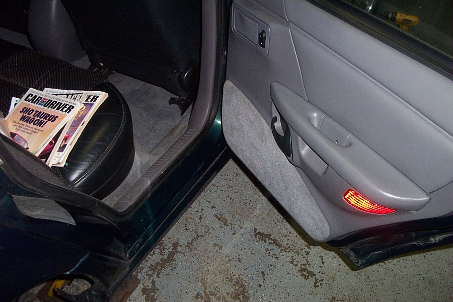 Interior door panel with magazines on the seat, one titled "SHO TAURUS WAGON!"