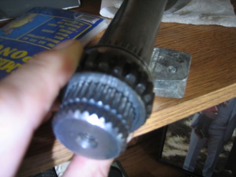 1986 Ford F-150 - A hand holds a splined shaft end, with a blue package and wooden shelf visible.