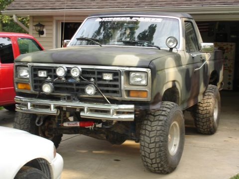 1979 Ford Bronco - This modified 1978 Ford Bronco is parked in front of a garage, with a red truck and a white car partially visible.