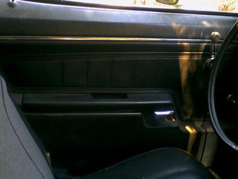 1973 Ford Ranchero - The interior door panel of a 1973 Ford Ranchero features a padded armrest and a chrome door handle.