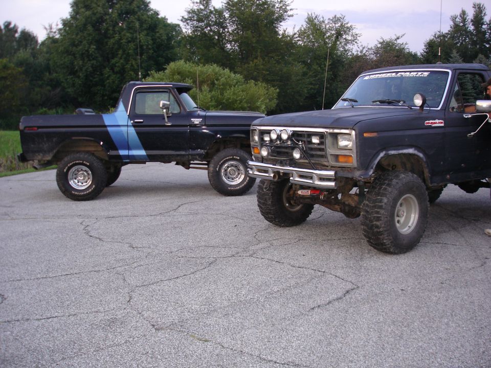 Black 1979 Ford F-150 pickup truck with blue stripe and a black 1979 Ford Bronco parked side-by-side