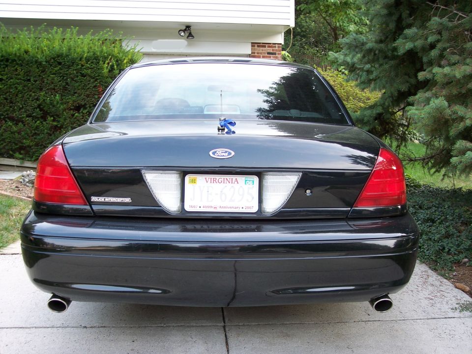 Rear view of black Ford Crown Victoria Police Interceptor with Virginia plate and dual exhaust in a driveway