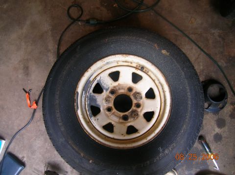 1996 Ford Bronco - A spare tire and rim are shown on a concrete floor, with some tools and a black cap visible.