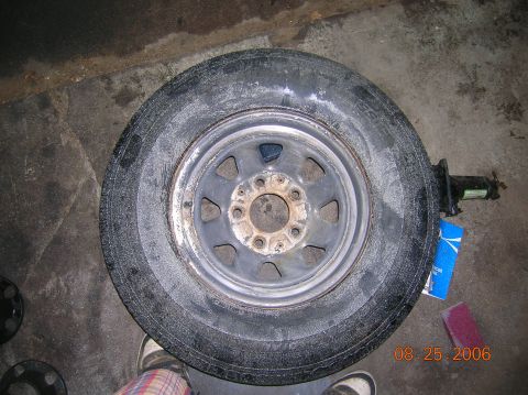 1996 Ford Bronco - A spare tire and wheel are shown on a concrete surface, with a jack and sanding block visible.
