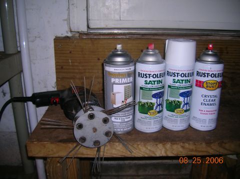 1996 Ford Bronco - A wire wheel brush attachment for a drill sits next to several cans of Rust-Oleum spray paint on a wooden workbench.