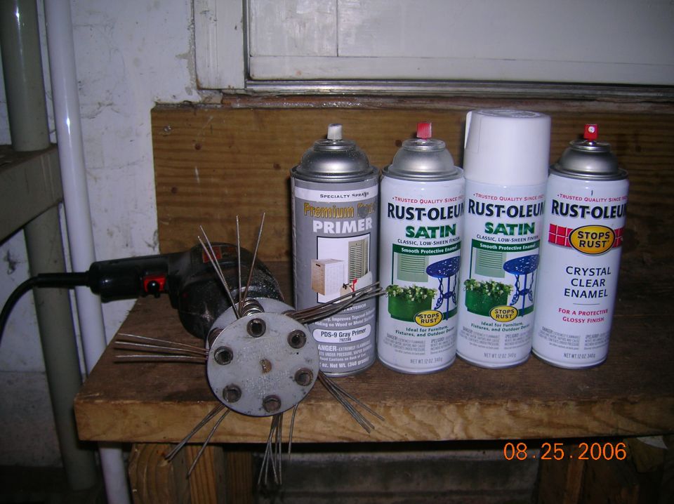 Wire wheel brush attachment and spray paint cans on a wooden surface