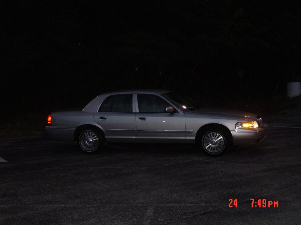 Silver sedan parked at night, side view. The car has a chrome grille and alloy wheels