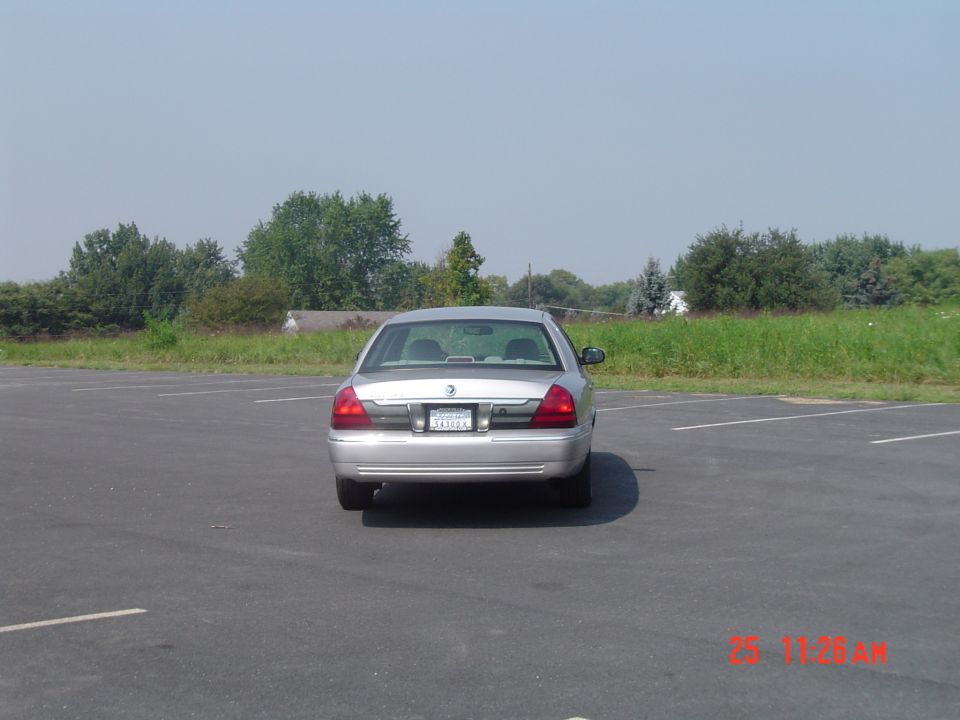 Silver sedan parked in an empty lot, rear view. License plate is visible