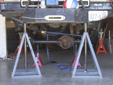 1991 Ford Bronco - The underside of a vehicle is raised on jack stands, showing the drivetrain and suspension components.