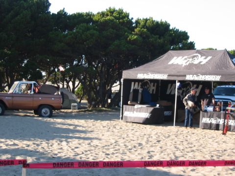 1995 Ford Bronco - A vintage Ford Bronco pickup is seen parked on a sandy beach, with a tent and a vendor booth nearby. The scene is marked with 'DANGER' tape.