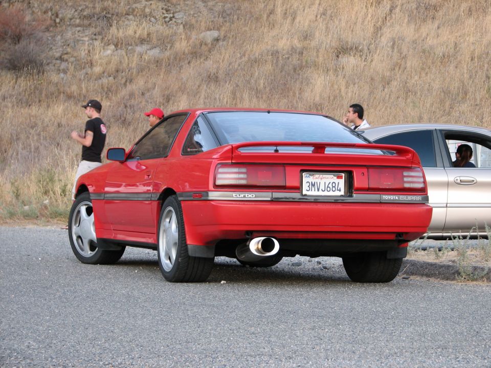 Red Toyota Supra Turbo coupe parked next to a silver sedan. California license plate 3MVJ684