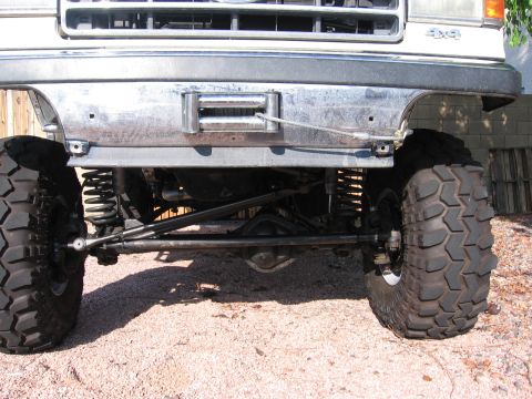 1990 Ford Bronco - Close-up of the front suspension and winch on a heavily modified 4x4 truck, with large off-road tires visible.