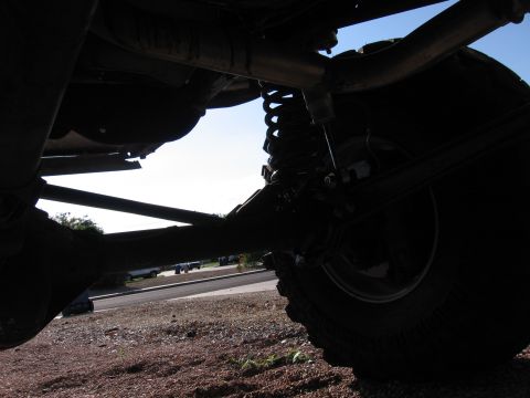 1990 Ford Bronco - Close-up view of the undercarriage, focusing on the suspension system and a large tire.
