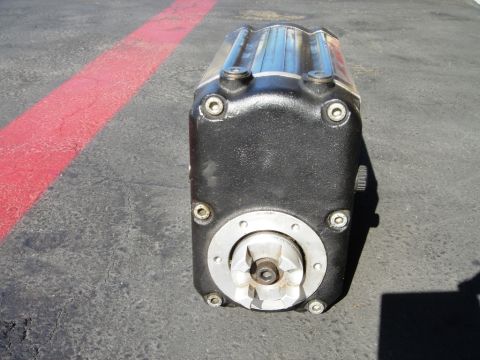 1991 Ford Taurus - This black engine part features a silver top and a circular connection for a drive shaft, shown outdoors on asphalt.