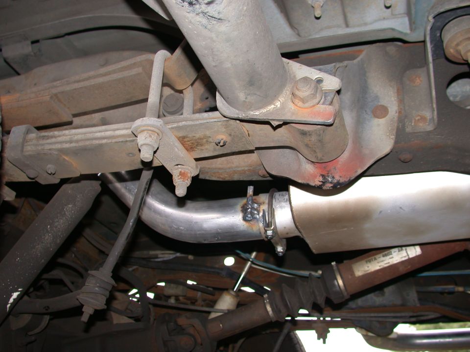 Vehicle undercarriage showing welded exhaust pipe, clamp, muffler and suspension parts