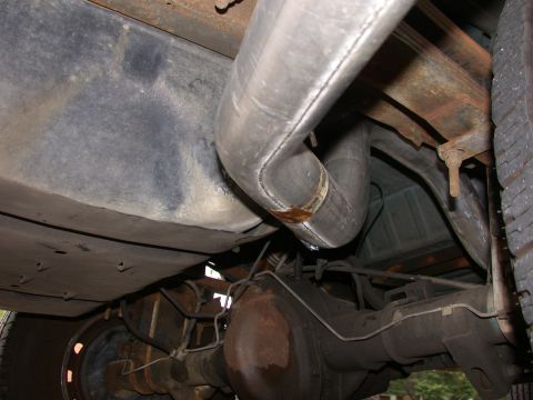 1995 Ford Bronco - Close-up view of the undercarriage of a vehicle, focusing on the exhaust system and rear axle components.