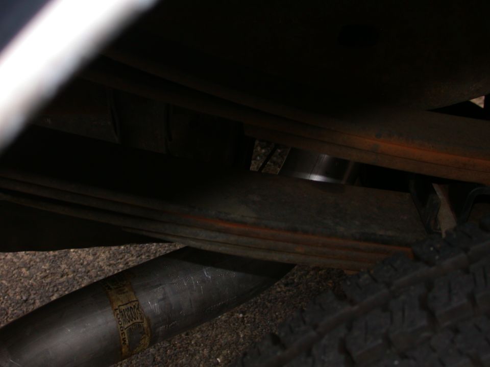 Undercarriage view of leaf spring suspension, exhaust pipe and tire edge
