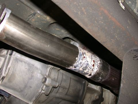 1995 Ford Bronco - Close-up view of a vehicle's exhaust pipe showing a temporary repair with tape and sealant.