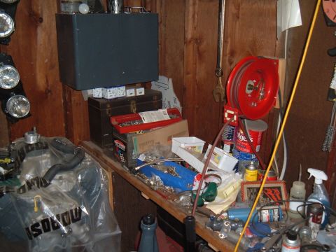 1971 Ford Ranchero - A cluttered workbench in a garage displays engine components and an assortment of tools and supplies.