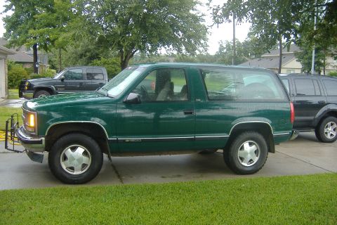 1994 Chevrolet Blazer - A green two-door SUV is parked in a driveway next to another vehicle.
