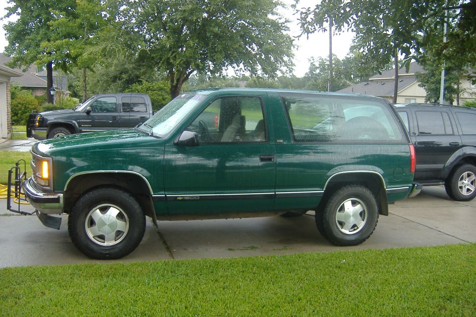 Green Chevrolet Blazer two-door SUV parked in driveway on overcast day