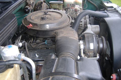 1994 Chevrolet Blazer - The engine bay of a green 1994 Chevrolet Blazer is shown, detailing various components.