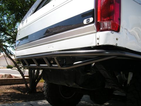 1993 Ford Bronco - The rear of a white Ford Bronco shows a custom tube bumper and a black stripe detail.